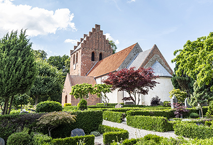 Kirken ligger højt, omgivet af træer, på en bakkekam nordligt i byen Skuldelev. 